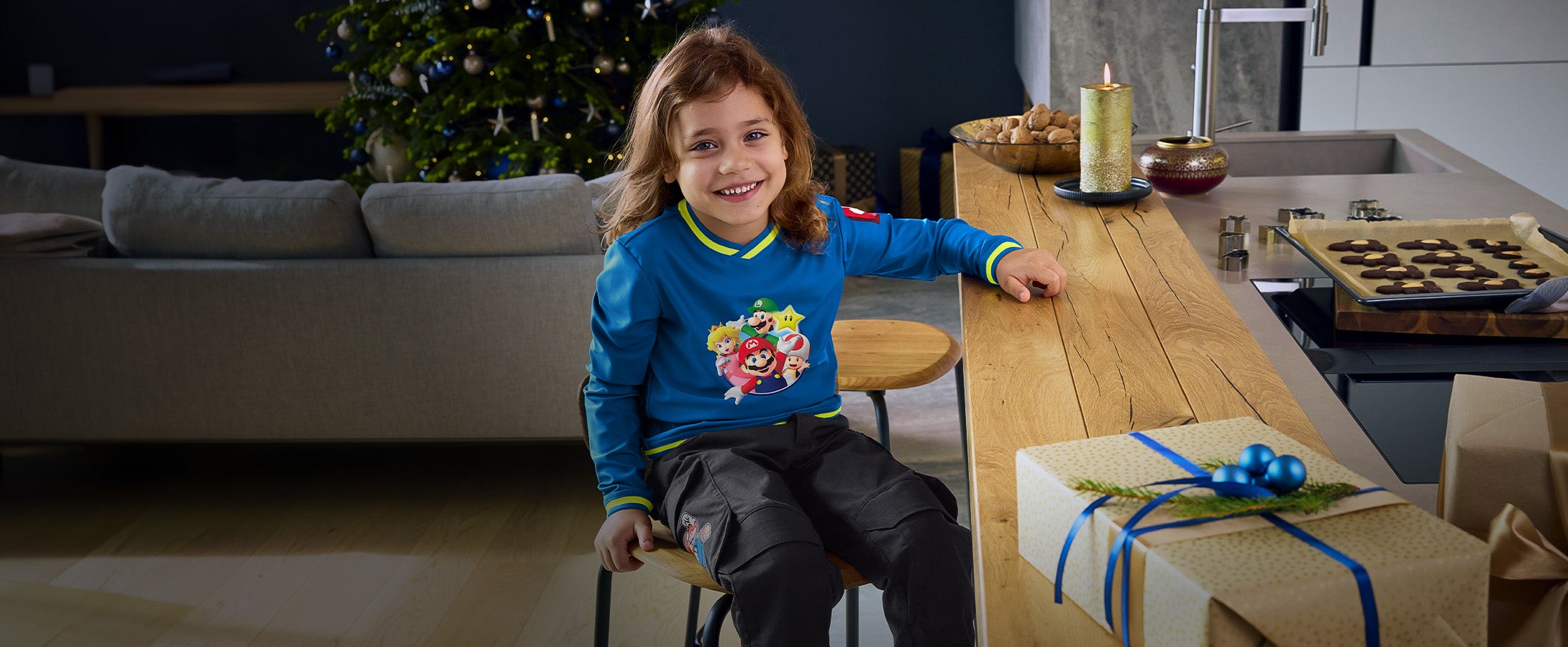 Meisje draagt kleding uit de Super Mario x Strauss-collectie in woonkamer in kerstsfeer