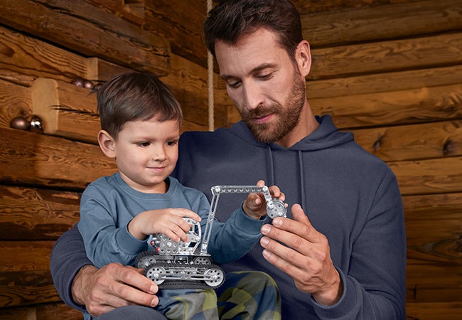 Meisje en jongen dragen kleding uit de Super Mario x Strauss-collectie in woonkamer in kerstsfeer
